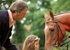 Trainer Henry Cecil is at hand as Princess Reema feeds grass to her father Prince Fahd Salman's Oaks winning filly Ramruma, named after her, at Newmarket June 21, 1999.