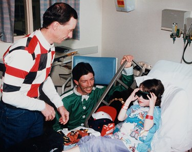 Bay Meadows Racetrack jockeys visit the Lucile Salter Packard Children's Hospital at Stanford, bringing gifts for numerous youngsters. Russell Baze helps Anna put on a pair of goggles as jockey Ken Tohill looks on Feb. 20, 1998.