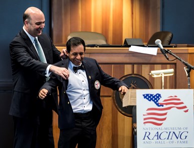 NYRA senior vice president Martin Panza helps jockey Victor Espinoza with his honorary jacket at the National Museum of Racing and Hall of Fame induction ceremony held Aug. 4, 2017 at the Fasig Tipton auditorium in Saratoga Springs, N.Y.