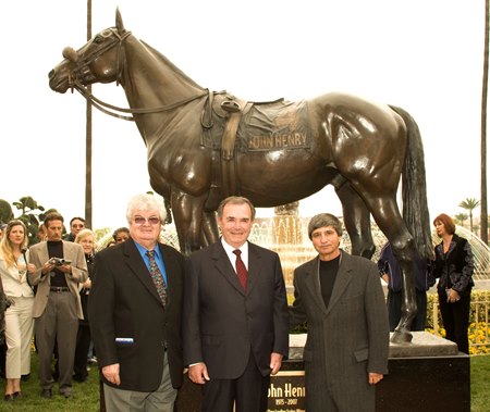 Hall of Fame trainer Ron McAnally (center) stands next to a statue of John Henry, flanked by two other horsemen that worked with John Henry, late trainers Eduardo Inda (left) and Lewis Cenicola (right)