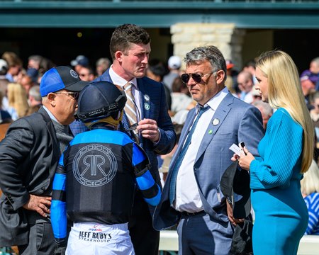 John Stewart (second from right) speaks to a rider wearing his Resolute Racing silks at Keeneland