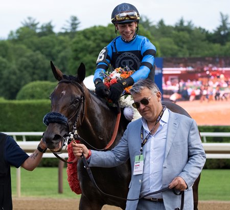 John Stewart of Resolute Racing leads Didia into the winner's circle after her victory in the New York Stakes at Saratoga Race Course