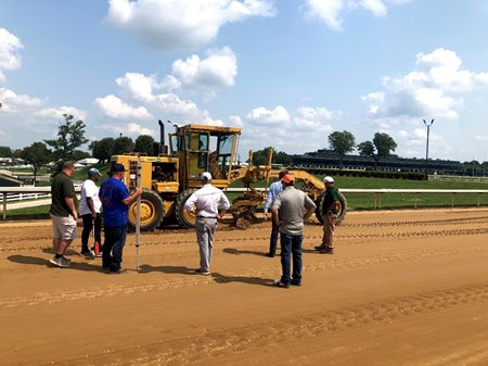 A crew examines a racetrack and maintenance equipment