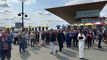 Potential bettors mingle while bookmaker representatives under umbrellas offer odds on Irish Derby day 2024 at the Curragh