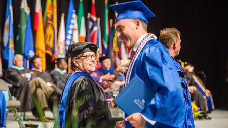 Nancy Cox congratulates a student during a commencement ceremony
