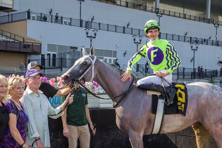 Michael Foster (purple cap) holds on to Next in the winner's circle after the Brooklyn Stakes at Aqueduct Racetrack