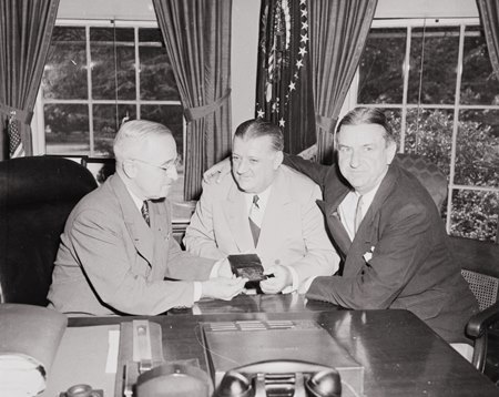 From left, President Truman receives his annual pass to NFL games from then commissioner Bert Bell and Washington owner George Marshall