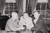 Photograph of President Truman at his desk in the Oval Office, receiving his annual pass to National Football League games from Bert Bell, Commissioner of the National Football League (center), and George Marshall, owner of the Washington Redskins.