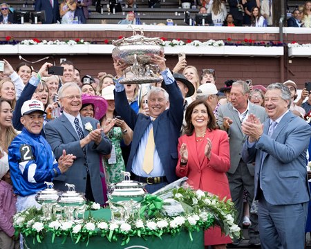 Godolphin's Michael Banahan raises the Belmont Stakes trophy as he celebrates with jockey Junior Alvarado, trainer Bill Mott, and New York Gov. Kathy Hochul at Saratoga Race Course