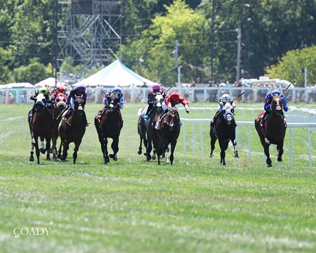 Tents and vehicles in the general admission section provide a backdrop as horses thunder down the stretch at Kentucky Downs