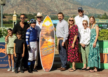 Trainer Michael McCarthy (right of surfboard) in the winner's circle after Stark Contrast won the Zuma Beach Stakes at Santa Anita Park