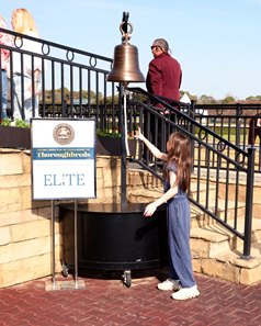 A youngster connected to a winning horse at Oaklawn Park rings the bell in the winner's circle in support of aftercare