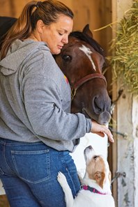 Cherie DeVaux interacts with Kentucky Derby winner Golden Tempo and her dog Reggie at her barn at Churchill Downs