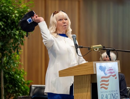 Dottie Ingordo-Sherriffs throws a ballcap into the crowd in honor of her late husband and Hall of Fame inductee John Shirreffs at the Racing Hall of Fame induction ceremony